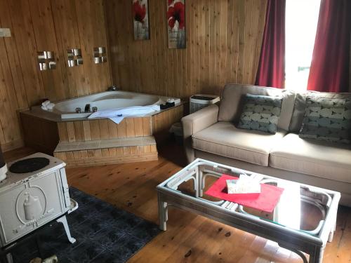 a living room with a couch and a tub at Auberge et Chalets sur le Lac in Lac-Mégantic