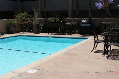 a swimming pool with two chairs and a table at O'Cairns Inn and Suites in Lompoc