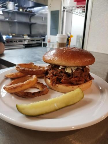 a sandwich and french fries and a pickle on a plate at O'Cairns Inn and Suites in Lompoc