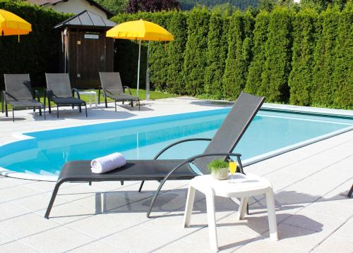 a chair and umbrella next to a swimming pool at Pension Sattlerenglhof in Laces
