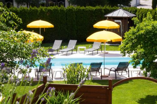 a group of chairs and umbrellas next to a pool at Pension Sattlerenglhof in Laces