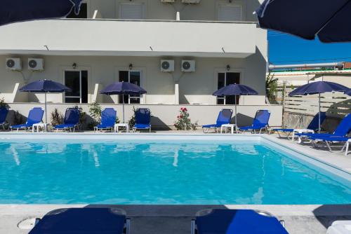 a swimming pool with blue chairs and umbrellas at Laganas Dreams 2 in Laganas
