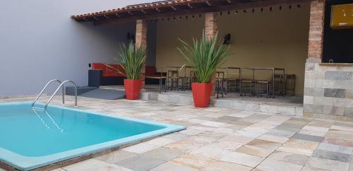 een patio met een zwembad en tafels en stoelen bij Vhostel in Uberlândia