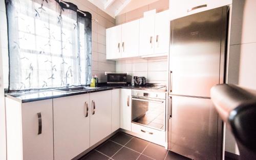 La cuisine est équipée de placards blancs et d'un réfrigérateur en acier inoxydable. dans l'établissement Casa Céu D'Abraão, à Piedade