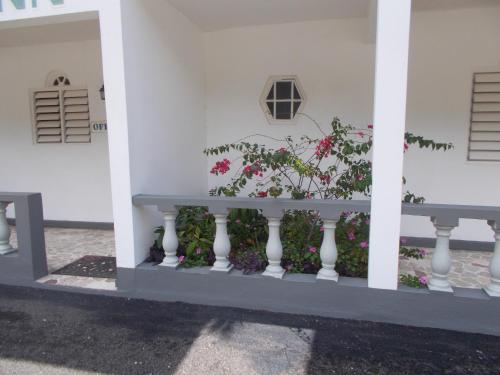 a white building with a white railing with pink flowers at Paradise Inn in Port Antonio