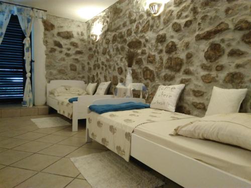 Habitación con 3 camas y pared de piedra. en Maestral, en Bribir