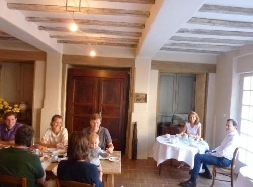 Un grupo de personas sentadas en una mesa comiendo en Le Logis Alexandra BnB, en La Trimouille