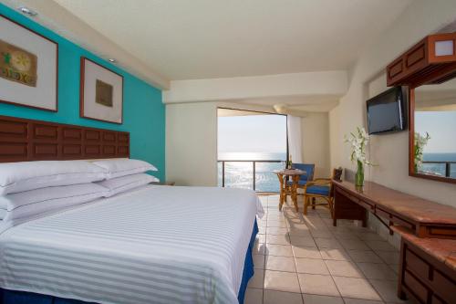 Schlafzimmer mit einem Bett, einem Schreibtisch und einem TV in der Unterkunft Barceló Ixtapa - All Inclusive in Ixtapa