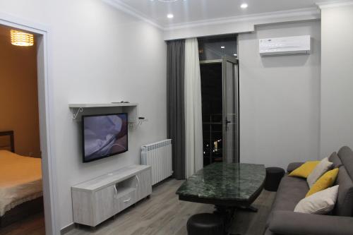 Una sala de estar con un sofá y un televisor en una pared. en Gio, en Batumi