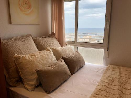 ein Schlafzimmer mit einem Bett mit Kissen und einem Fenster in der Unterkunft Apartamento & sea view in Alicante