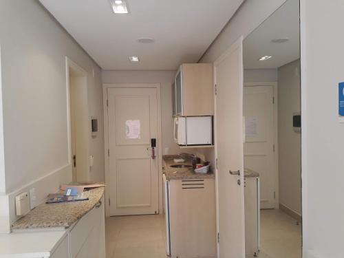 a kitchen with white cabinets and a refrigerator at ApartHotel no Jurerê Beach Village in Florianópolis