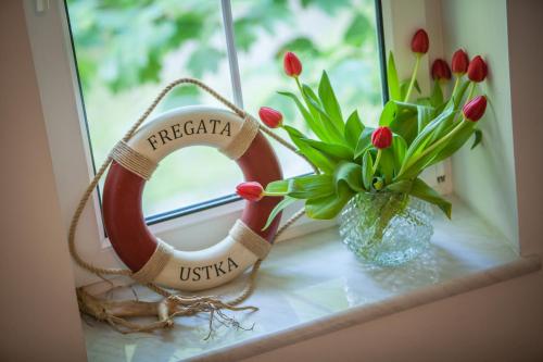 a life preserver on a window with a vase of flowers at Fregata in Ustka