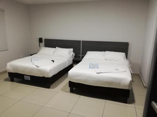 two beds in a hotel room with white sheets at Hotel Doral Inn in Ibagué