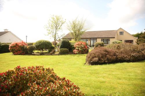 a house with a yard with bushes and flowers at Torine House B&B in Killorglin