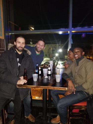 a group of men sitting at a table with bottles of beer at Hamtramck Hostel in Detroit