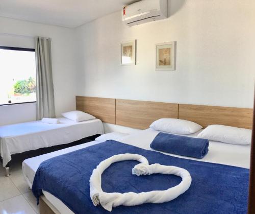 a hotel room with two beds with a heart shaped bedvisor at Maragogi Praia Flats in Maragogi