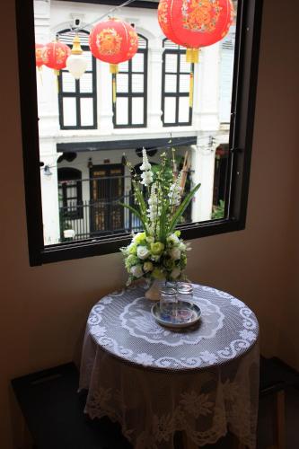 a table with a vase of flowers in a window at Ming Shou Boutique House in Phuket Town