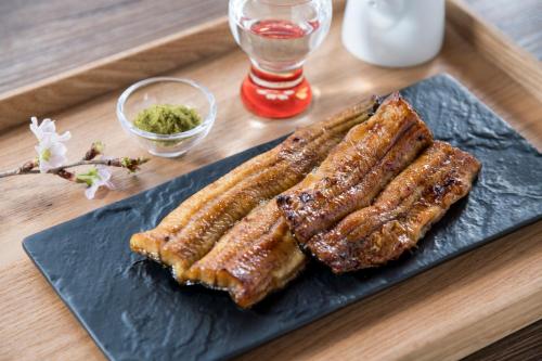 a black plate with three pieces of meat on a table at HOTEL MYSTAYS PREMIER Sapporo Park in Sapporo