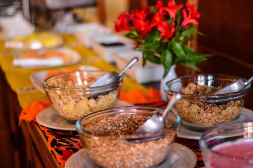 a table with bowls of food and a vase with red flowers at Hotel Diego de Mazariegos in San Cristóbal de Las Casas