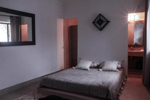 Schlafzimmer mit einem Bett und einem Wandspiegel in der Unterkunft Riad DAR HOME in Marrakesch