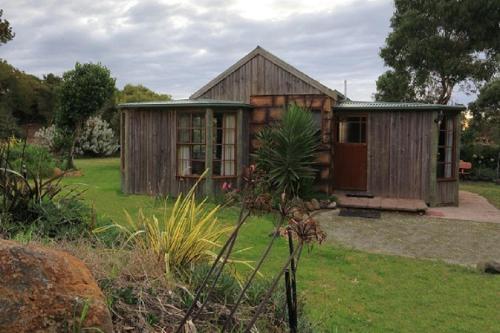 
a small house with a wooden roof and a garden at Stanley Lakeside Spa Cabins in Stanley
