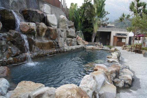 a swimming pool with a waterfall and a water feature at Go Ya Hot Spring in Heping