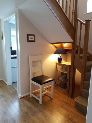 a stairway with a chair and a desk in a room at The Beekeeper's Cottage in Saint Columb Major
