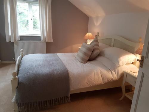 a bedroom with a bed with white sheets and a window at Leghorn Cottage in Saint Columb Major