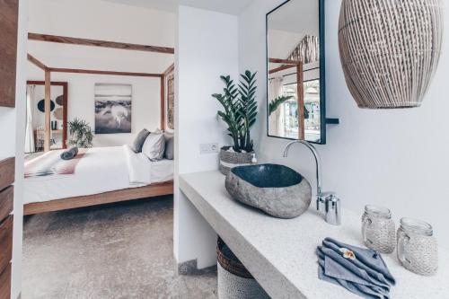 a bathroom with a sink and a bedroom with a bed at Beyond Bungalows in Canggu