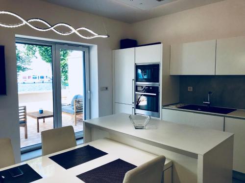 une cuisine avec des placards blancs et une table avec des chaises dans l'établissement Apartments & rooms Artemus Belveder, à Koper