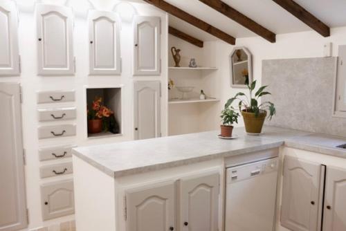 une cuisine blanche avec des placards blancs et une cheminée dans l'établissement Les murmures du Temps Villa 3 Chambres avec Piscine, à Carpentras
