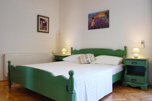 a bedroom with a green bed with two night stands at Apartment and rooms Jurišić in Korčula