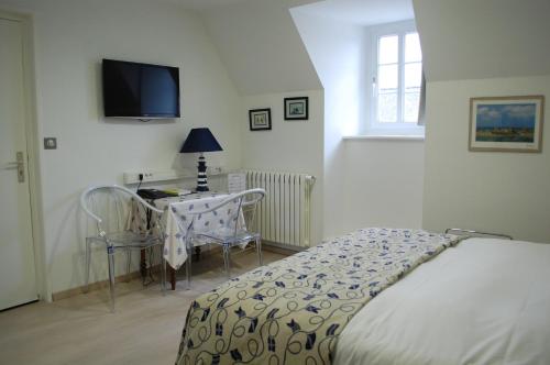 1 dormitorio con cama, mesa y TV en Logis Hotel L'europe, en Pontivy