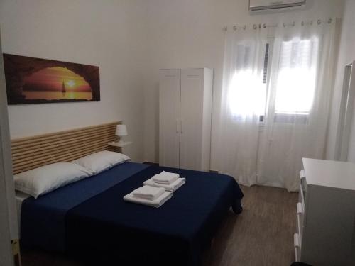 ポルト・エンペードクレにあるCasa Vacanze A Due Passi Dal Mareのベッドルーム1室(ブルーベッド1台、タオル付)
