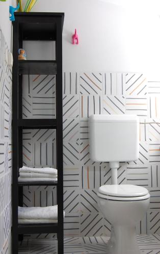 a bathroom with a toilet and a geometric wallpaper at Apartment and rooms Jurišić in Korčula