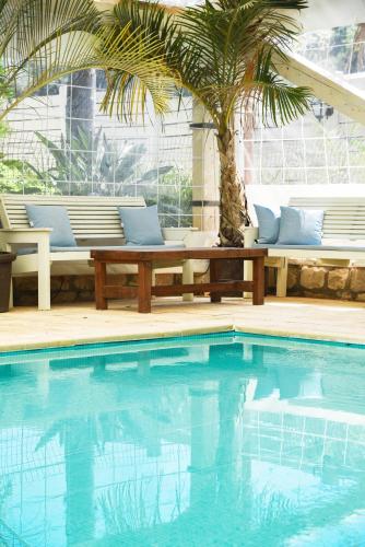 a swimming pool with a bench and a palm tree at The White Chalet View in Moshav Ramot