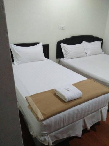two beds in a room with white sheets and towels at Hotel Sri Malim Sungkai in Sungkai