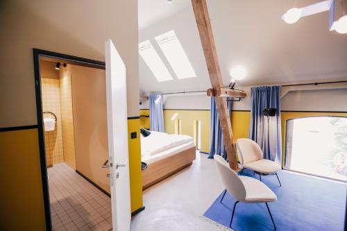 ein Schlafzimmer mit einem Bett und zwei Stühlen in einem Zimmer in der Unterkunft Hotel am Kloster - Domäne Möllenbeck in Rinteln