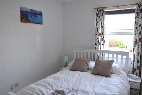 a white bed in a bedroom with a window at Stunning Seaview Cottage in St Just