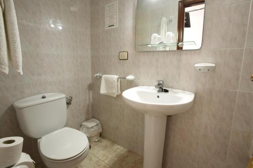 a white bathroom with a toilet and a sink at Hostal San Roque in Portonovo