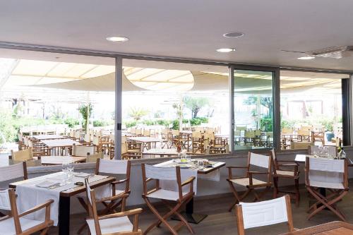 a restaurant with wooden tables and chairs and windows at Hotel Tirreno in Spotorno