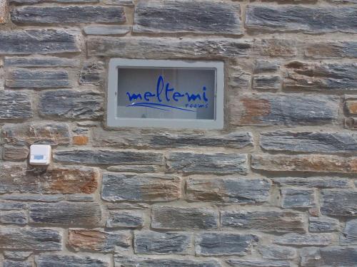 a sign on a brick wall with blue graffiti at Meltemi in Vourkarion