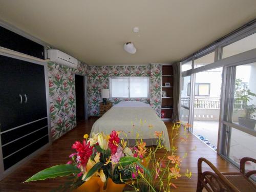 um quarto com uma cama e uma mesa com flores em Tomonoya Ishigaki em Ishigaki