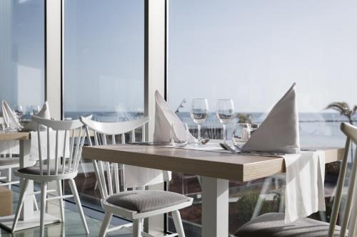 a table and chairs with wine glasses and a window at Arrecife Gran Hotel & Spa in Arrecife