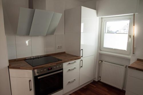 a kitchen with white cabinets and a window at FeWo zur Sonne in Herdecke