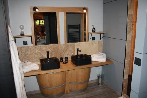 a bathroom with two sinks and a mirror at La Cabane à Papi in Thénac