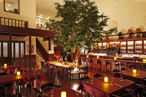 un restaurant avec des tables et des chaises et un arbre au milieu dans l'établissement Hotel Boston Plaza Kusatsu, à Kusatsu