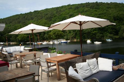 a patio with tables and chairs and umbrellas at Merlin les pieds dans l'eau in Saint-Aignan