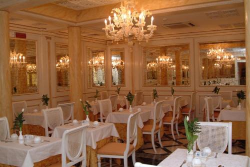 a restaurant with white tables and chairs and a chandelier at Hotel Belle Epoque in Venice