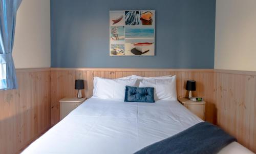 a bedroom with a white bed with a blue pillow at Beachcomber Holiday Park in Potato Point